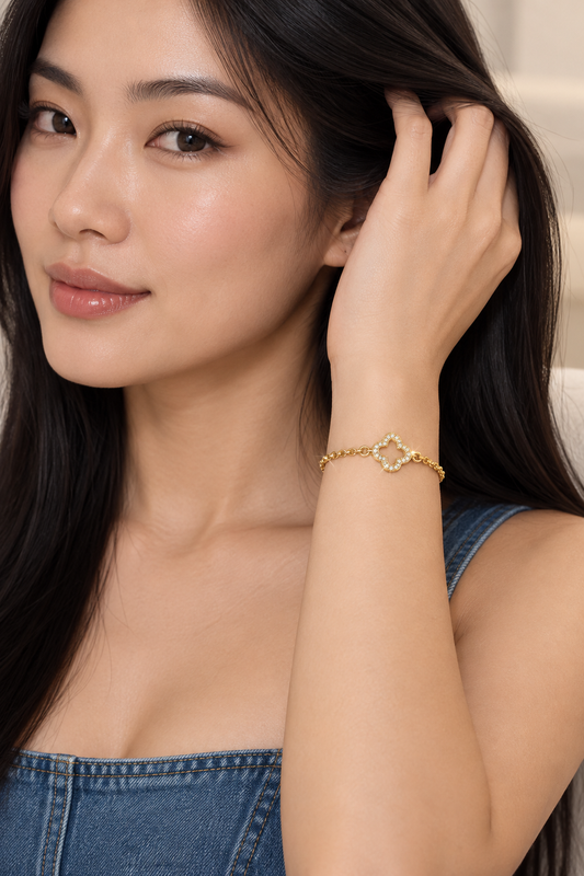 Asian model in a denim top running her hand through her hair, wearing the gold clover connector bracelet
