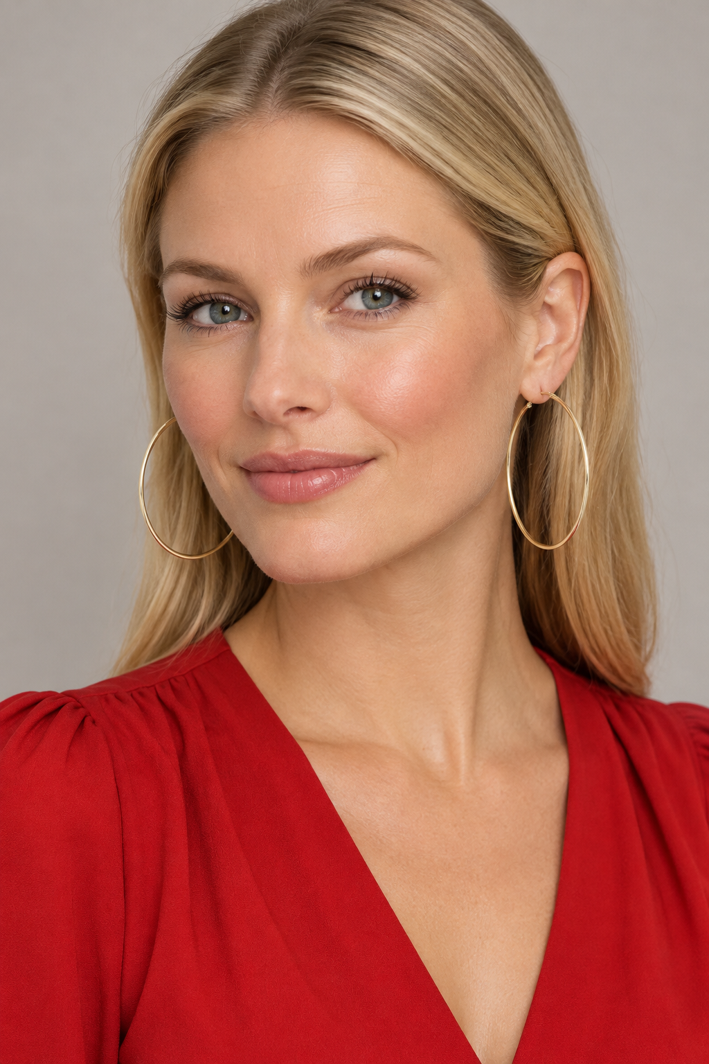 Blonde model in a red blouse wearing the gold hoop earrings