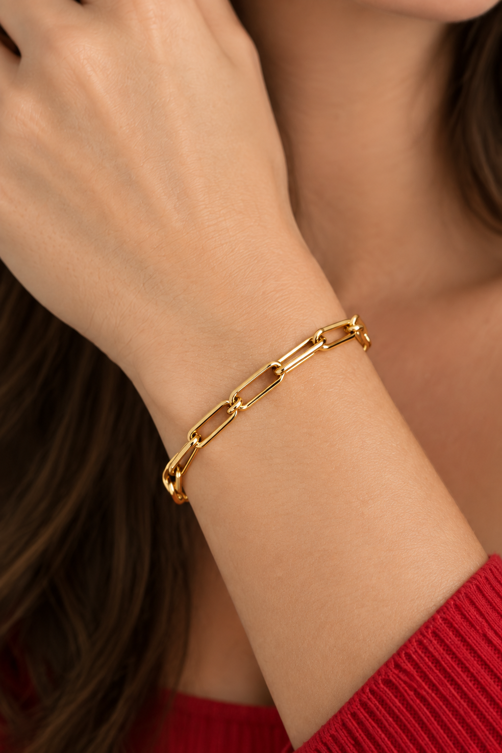 Close-up of a wrist wearing the gold filled paper clip link bracelet with a red sleeve